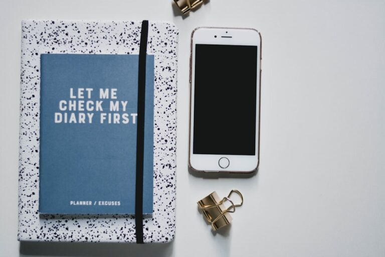Person writing a financial checklist for beginners in a notebook at a desk