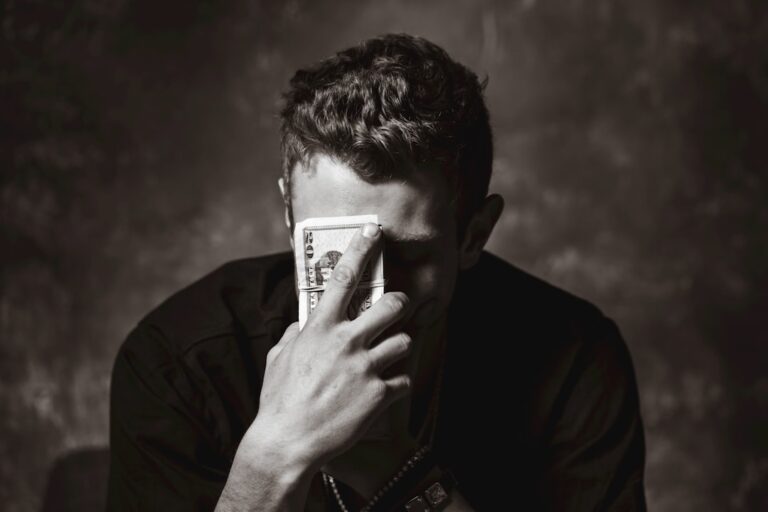 Person sitting at a desk surrounded by bills and a laptop, deciding whether to pay off debt or invest first