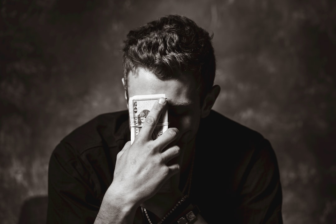 Person sitting at a desk surrounded by bills and a laptop, deciding whether to pay off debt or invest first