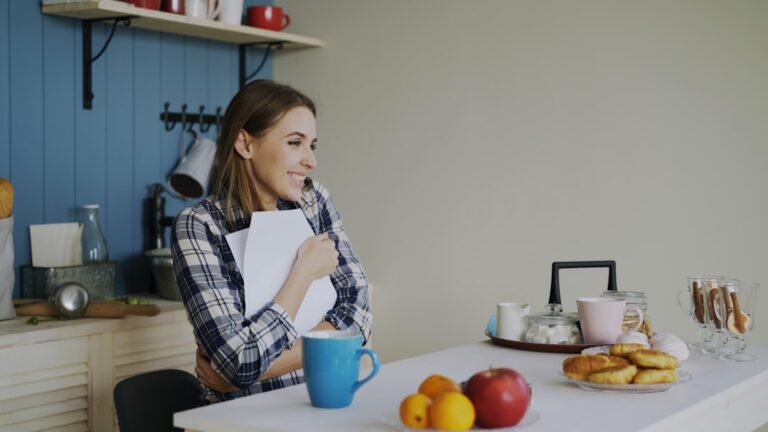 Person sitting at kitchen table looking stressed while reviewing bills, illustrating the challenge of covering a $2,000 emergency without savings
