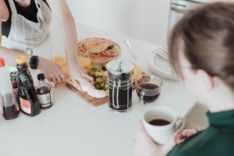 A couple sits at a kitchen table having an honest conversation about combining finances when one partner has debt