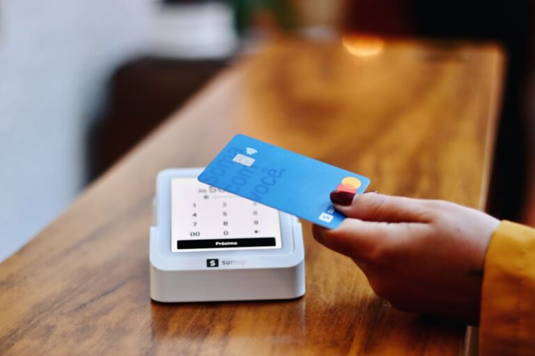 Person holding a credit card and reviewing their credit utilization rate on a statement at home