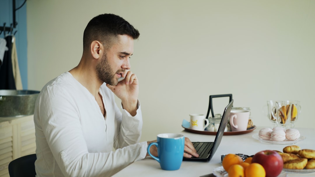 A man in his late 40s sitting at a home desk looking thoughtfully at papers, representing the financial decisions facing someone laid off over 45