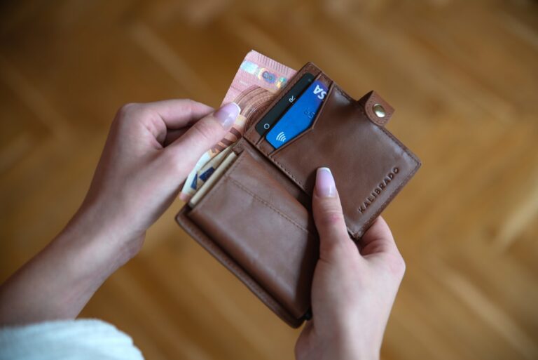 A person holding a secured credit card and cash, comparing a secured card vs credit-builder loan for rebuilding credit