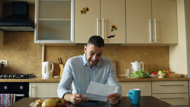 Person reviewing money market account statements at kitchen table, considering retirement savings options
