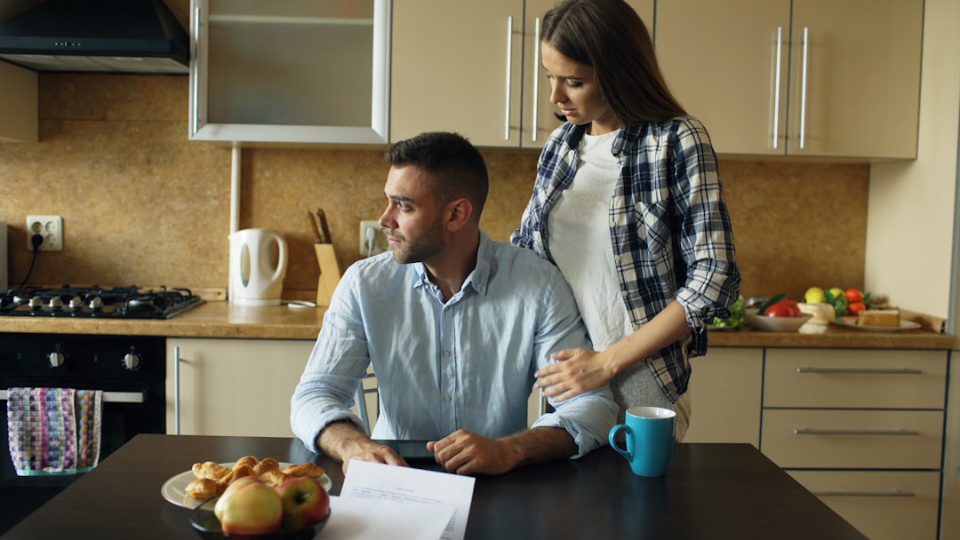 Woman calculating her net worth at 40 at a kitchen table with a notebook and laptop