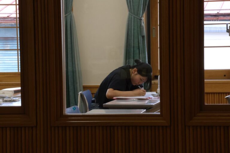 Person sitting at a desk surrounded by student loan debt paperwork, illustrating student loan debt statistics in 2026