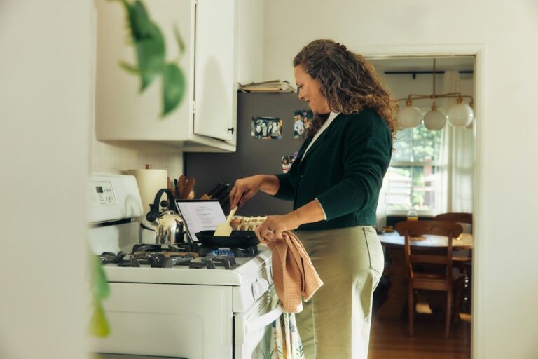 Woman sitting at kitchen table reviewing bills and financial documents while considering a 401k loan while in debt