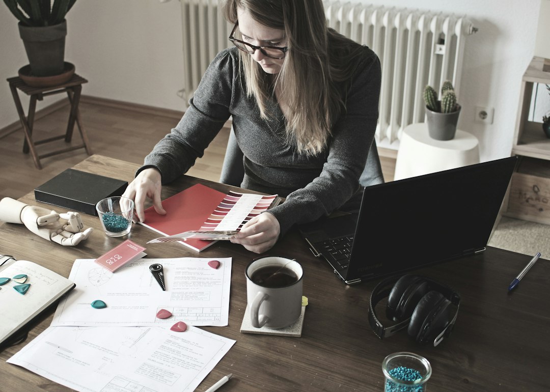 A woman reviewing bills and making manual payments on her laptop at a kitchen table — autopay vs manual bill payment decision