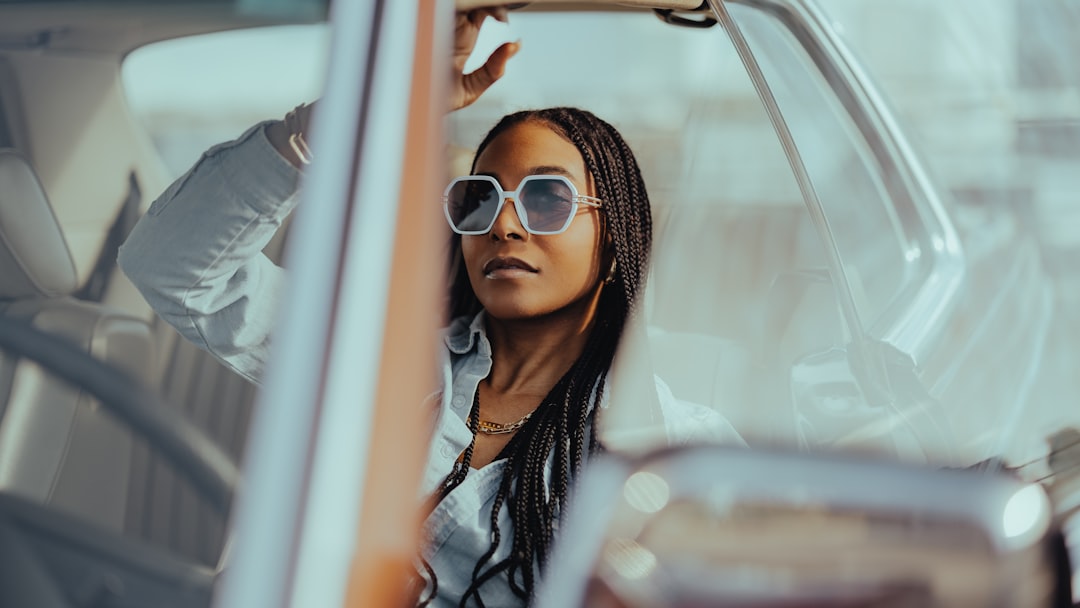 Woman standing next to a car at a dealership, considering how much car she can afford