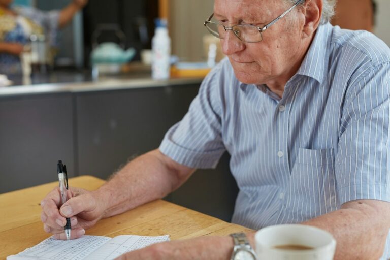 Older couple reviewing credit card bills and retirement paperwork at kitchen table, planning how to manage retirement credit card debt